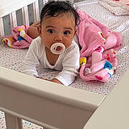Zenobia joined the competition — help win amazing prizes! baby, pacifier, crib, blanket, infant, tummy_time, cute, child, white_clothing, pink_blanket, bedroom, furniture, home, sleeping_area, person, face, looking, indoors, soft, rest