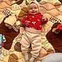 Ayla joined the competition — help win amazing prizes! baby, smiling, headband, red_clothing, pants, socks, quilt, toy, soft_toy, play_area, infant, child, lying_down, cute, happy, indoors, patterned_background, baby_girl, cozy, portrait
