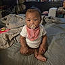 baby, child, infant, sitting, pacifier, bib, shirt, bed, bedroom, blanket, bedding, portrait, face, eyes, hair, indoors, furniture, exercise_ball, toys, home