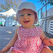 Diane participe au concours pour gagner de l'argent avec cette photo : baby, child, smiling, hat, sunhat, dress, pink, floral_pattern, outdoor, daylight, sky, tent, happy, person, sitting, face, cute, summer, nature, playful