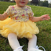 Melina is registered to the contest to win money with this photo: baby, child, grass, outdoor, dress, yellow_tutu, white_tights, sneakers, untied_laces, smiling, sitting, nature, trees, sky, cute, infant, portrait, daylight, happy, playful