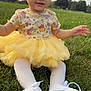 baby, child, grass, outdoor, dress, yellow_tutu, white_tights, sneakers, untied_laces, smiling, sitting, nature, trees, sky, cute, infant, portrait, daylight, happy, playful