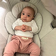 Elani is registered to the contest to win money with this photo: baby, infant, child, baby_seat, cushion, white_shirt, pink_pants, socks, indoor, portrait, cute, hands, clothing, person, young_child, resting, looking_up, comfort, soft, seat