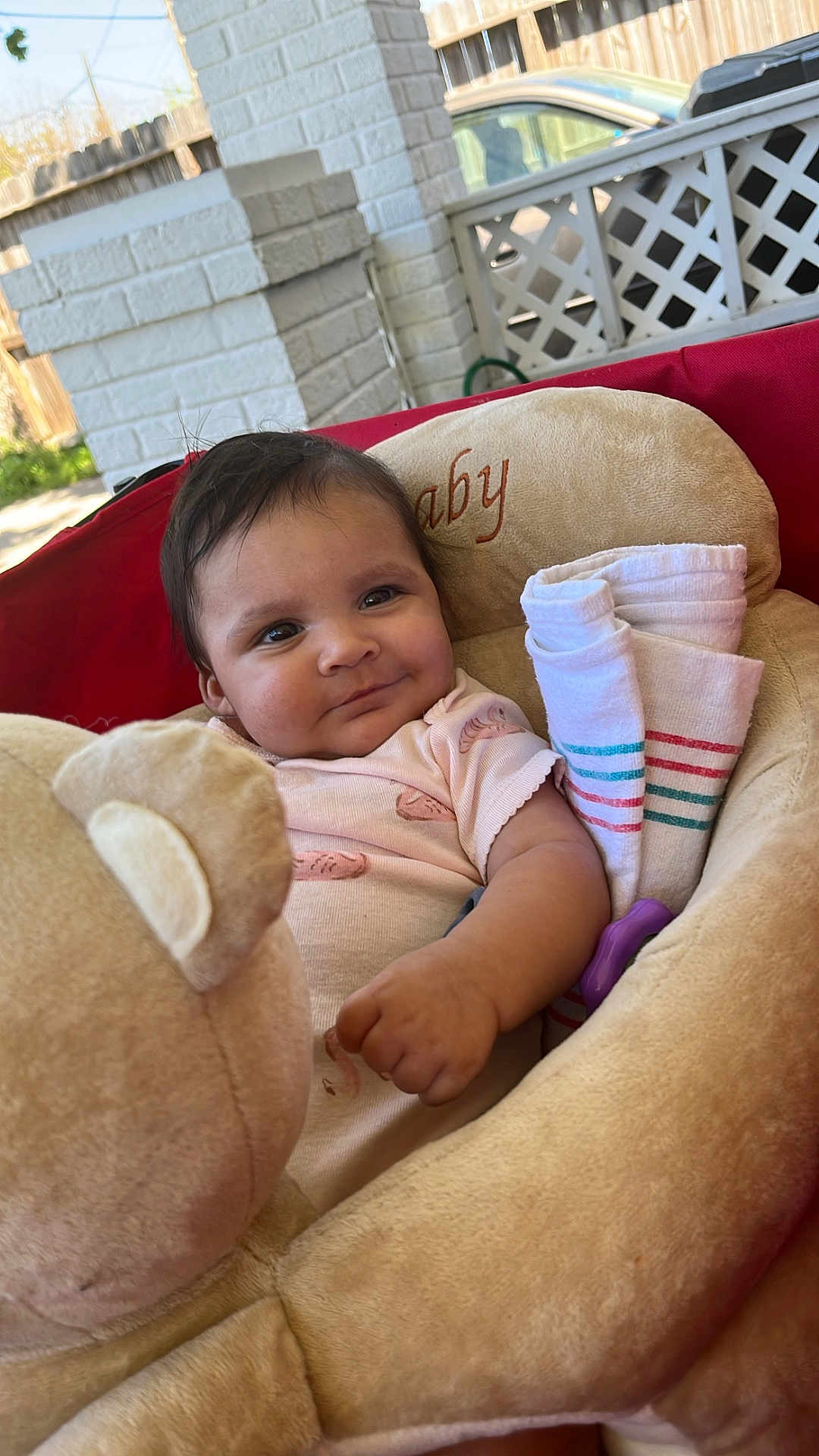 Essence joined the competition — help win amazing prizes! baby, child, plush_toy, seat, comfort, outdoor, brick_wall, wooden_fence, car, clothing, smile, face, arm, rolled_cloths, pink, soft_toy, person, sunlight, portrait, cuteness