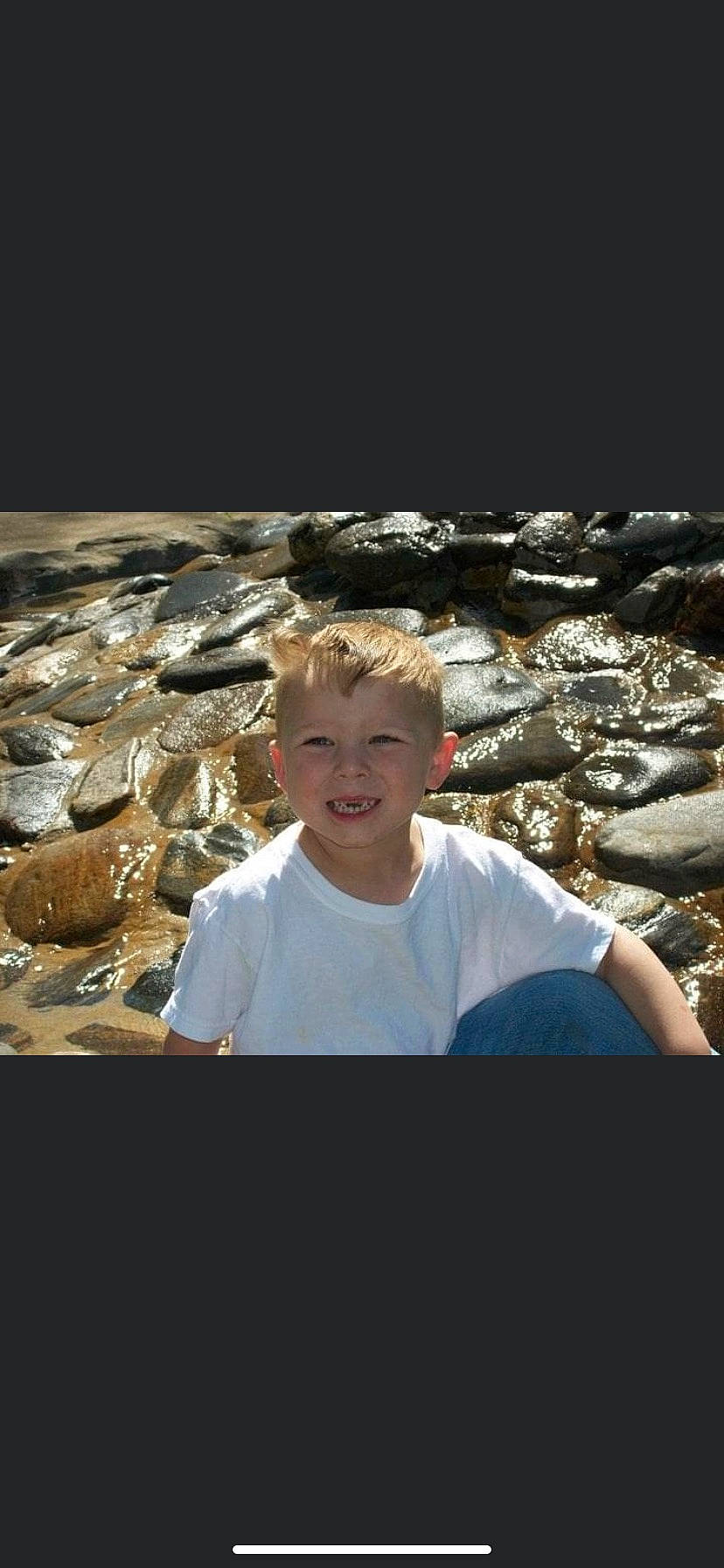 Chris is registered to the contest to win money with this photo: bedrock, child, eye, eyewear, flash_photography, fun, grass, happy, human_body, joy, landscape, leisure, person, rock, sitting, smile, soil, t_shirt, toddler, travel