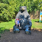 Emerie joined the competition — help win amazing prizes! child, statue, bear, park, outdoor, greenery, sunhat, grass, fence, smiling, summer, nature, playground, daylight, happy, sculpture, person, feet, clothing, trees