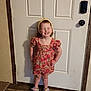 Emerie is registered to the contest to win money with this photo: child, girl, smiling, standing, dress, floral_pattern, headband, indoors, door, floor, shoes, happy, person, skin, hair, hand, pose, casual, home, young