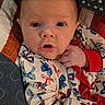 baby, infant, face, person, clothing, hand, quilt, pattern, red, white, blue, bow, cute, portrait, expression, newborn, soft, cozy, sleepwear, closeup
