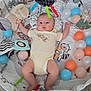 baby, infant, playpen, toy, stuffed_animal, ball, carpet, floor, clothing, onesie, face, child, indoor, cute, colorful, soft_toy, patterned, lying_down, curious, padded