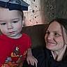 Joshua is registered to the contest to win money with this photo: adult, black_clothing, blue_hat, cartoon_clothing, child, couch, family, floral_curtains, funny_hat, home, indoor, photograph, portrait, red_shirt, serious_expression, sitting, smiling, toddler, two_people, woman