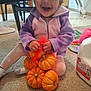 Ivy'Ann is registered to the contest to win money with this photo: toddler, child, pumpkins, net_bag, carpet, milk_gallon, toy, purple_hoodie, pink_hoodie, indoor, floor, smiling, happy, sitting, clothing, person, small_pumpkins, home, playful, cute