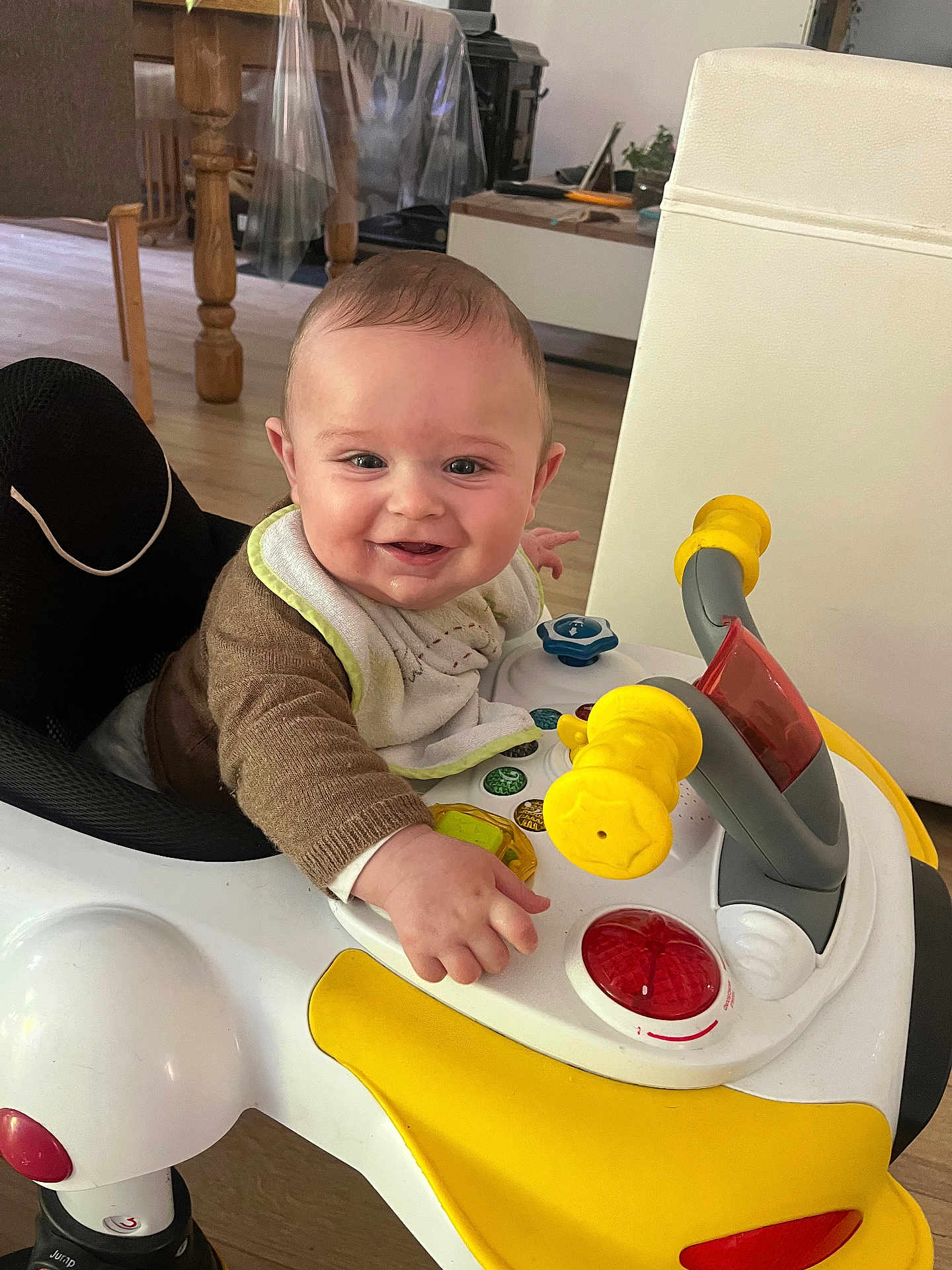 Marius participe au concours pour gagner de l'argent avec cette photo : baby, walker, toy, smile, indoor, child, bib, clothing, floor, wooden_furniture, table, chair, happy, person, play, face, hand, light, household, flooring
