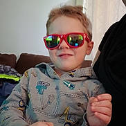 Oliver is registered to the contest to win money with this photo: child, sunglasses, hoodie, indoor, couch, smile, person, hand, glasses, face, furniture, curtain, window, photography, portrait, casual, young, light, home, decor