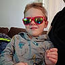 child, sunglasses, hoodie, indoor, couch, smile, person, hand, glasses, face, furniture, curtain, window, photography, portrait, casual, young, light, home, decor