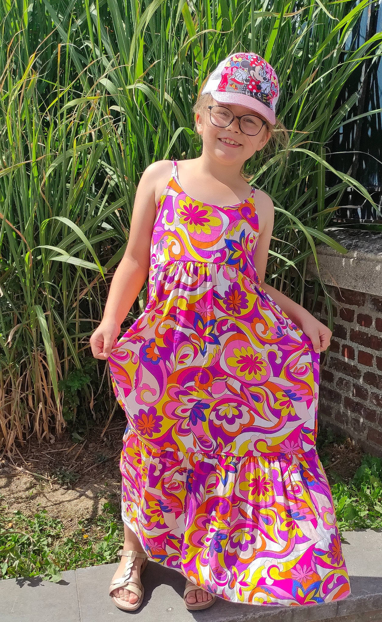 Noémie participe au concours pour gagner de l'argent avec cette photo : baby_toddler_clothing, clothing, day_dress, dress, fashion_design, fawn, glasses, grass, headwear, joy, leg, magenta, one_piece_garment, people_in_nature, person, pink, plant, shoulder, smile, summer