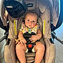 baby, car_seat, infant, child, seatbelt, fan, indoor, clothing, foot, hand, face, safety, cute, expression, comfort, patterned, looking, light, floor, strap