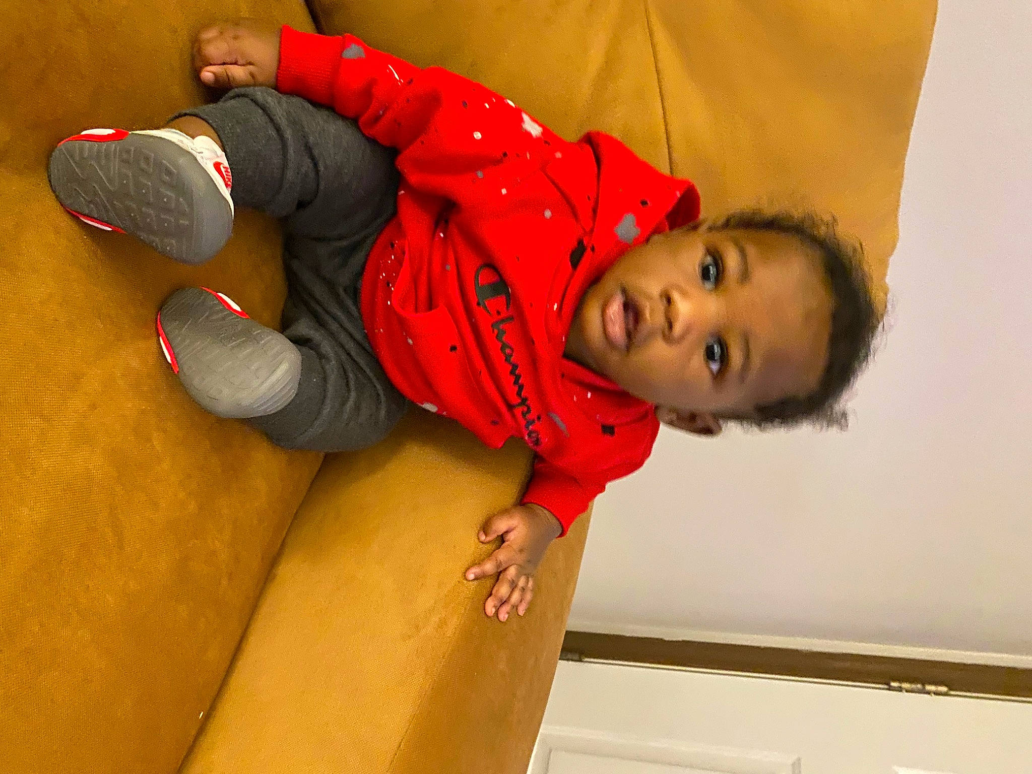 Samair is registered to the contest to win money with this photo: carmine, child, comfort, elbow, flooring, fun, hat, human_leg, joint, knee, orange, person, room, sitting, sleeve, smile, thigh, toddler, wood