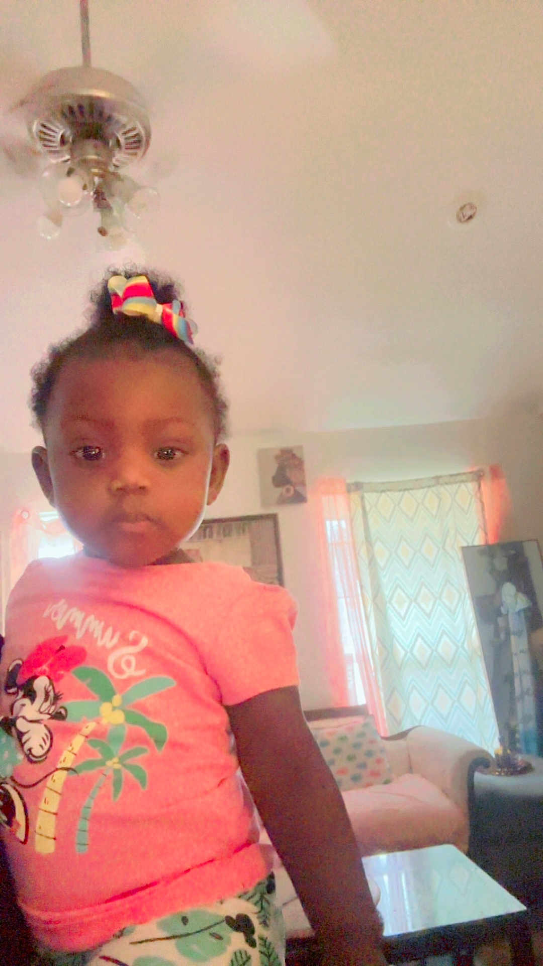 Angelia joined the competition — help win amazing prizes! toddler, child, indoor, living_room, pink_shirt, bow, minnie_mouse, curious, furniture, curtains, table, sofa, patterned, casual_clothing, portrait, person, young_child, home, cute, girl