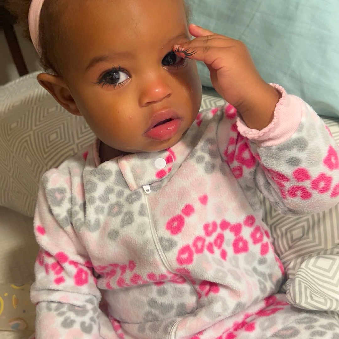 Sommer joined the competition — help win amazing prizes! baby, bed, child, cozy, cute, expression, eye, face, gray, hair, hand, headband, indoor, leopard_print, onesie, pillow, pink, sitting, soft_lighting, toddler