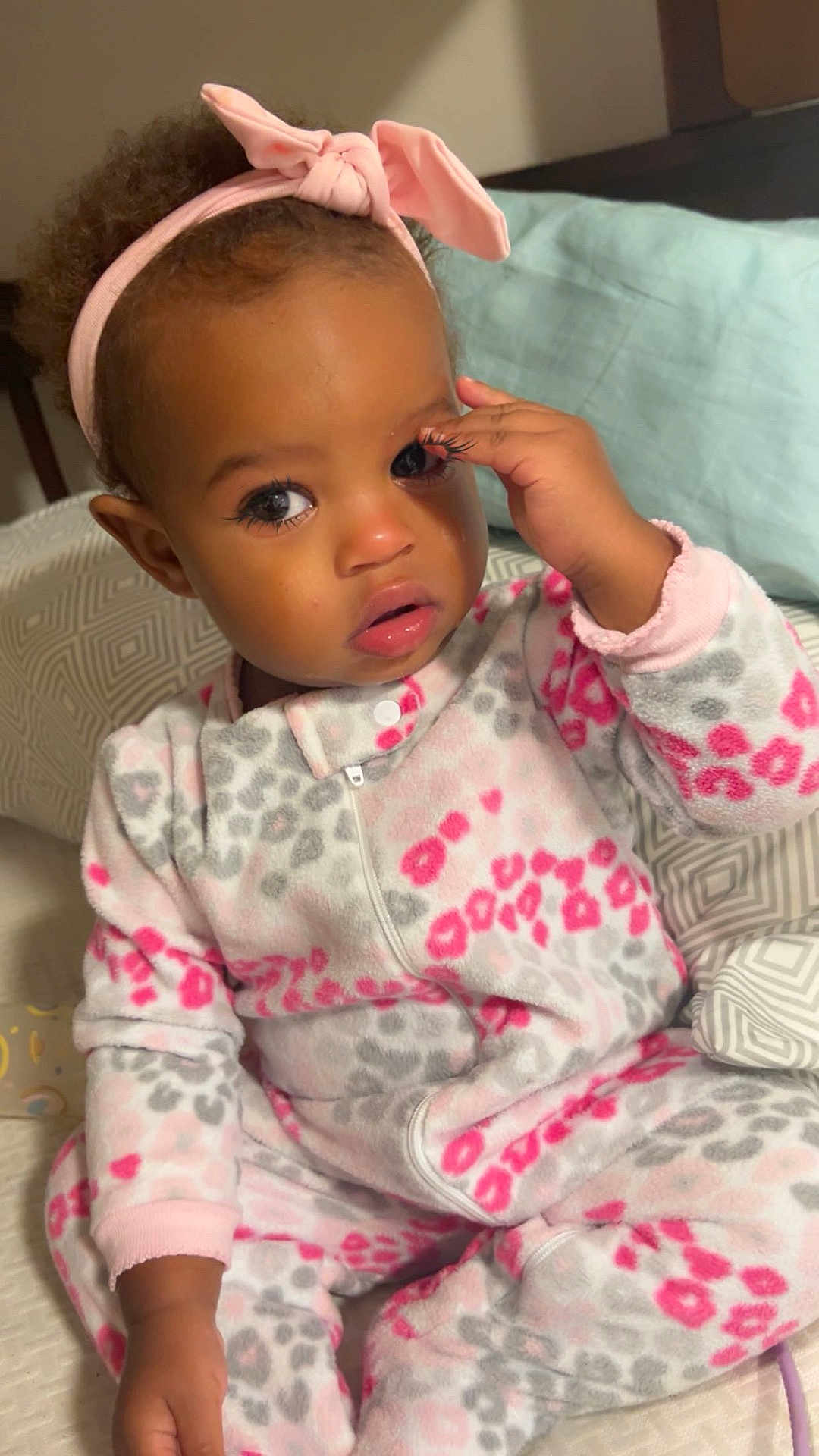 Sommer joined the competition — help win amazing prizes! toddler, child, onesie, headband, pink, gray, leopard_print, bed, pillow, hand, face, eye, hair, cozy, indoor, cute, baby, sitting, expression, soft_lighting