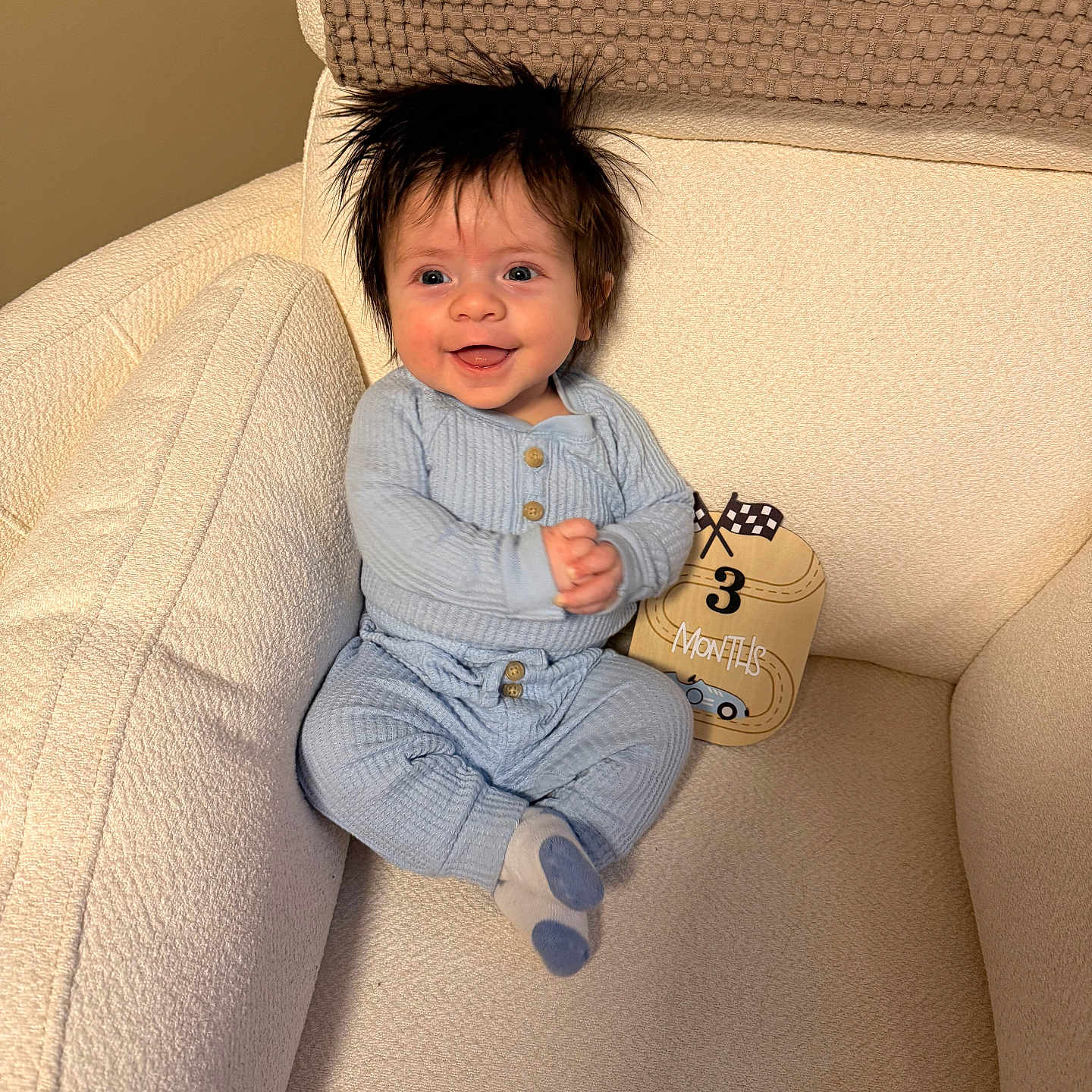 Bennett joined the competition — help win amazing prizes! armchair, baby, blue_onesie, cozy, cushion, hands_clasped, happy, indoor, infant, milestone, milestone_card, nursery, portrait, sitting, smiling, socks, soft_lighting, spiky_hair, textured_fabric, three_months