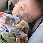 Dale is registered to the contest to win money with this photo: baby, sleeping, pacifier, blanket, car_seat, child, safety_warning, clothing, infant, cute, peaceful, fabric, clip, resting, indoors, closeup, head, face, nap, soft