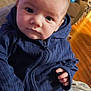 Dale is registered to the contest to win money with this photo: baby, child, face, hoodie, striped_pants, indoor, living_room, couch, toy, floor, person, clothing, hand, seated, infant, curious, casual, portrait, home, cozy