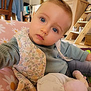 Alba participe au concours pour gagner de l'argent avec cette photo : baby, child, face, blue_eyes, vest, green_shirt, indoor, home, toy, plush, furniture, wooden_chair, shelf, decor, photography, portrait, curious, candid, seated, closeup