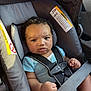 baby, blue_onesie, car_interior, car_seat, child, closeup, curly_hair, cute, human, indoors, infant, person, safety_harness, seat, seatbelt, serious_expression, sitting, straps, transportation, young_child