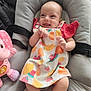 Linoa a rejoint le concours — aidez-le/la à gagner de superbes lots ! baby, infant, smiling, dress, fruit_pattern, pink_elephant_toy, seat, cushion, happy, tongue_out, indoor, child, clothing, playful, toy, person, cute, colorful, comfortable, joyful