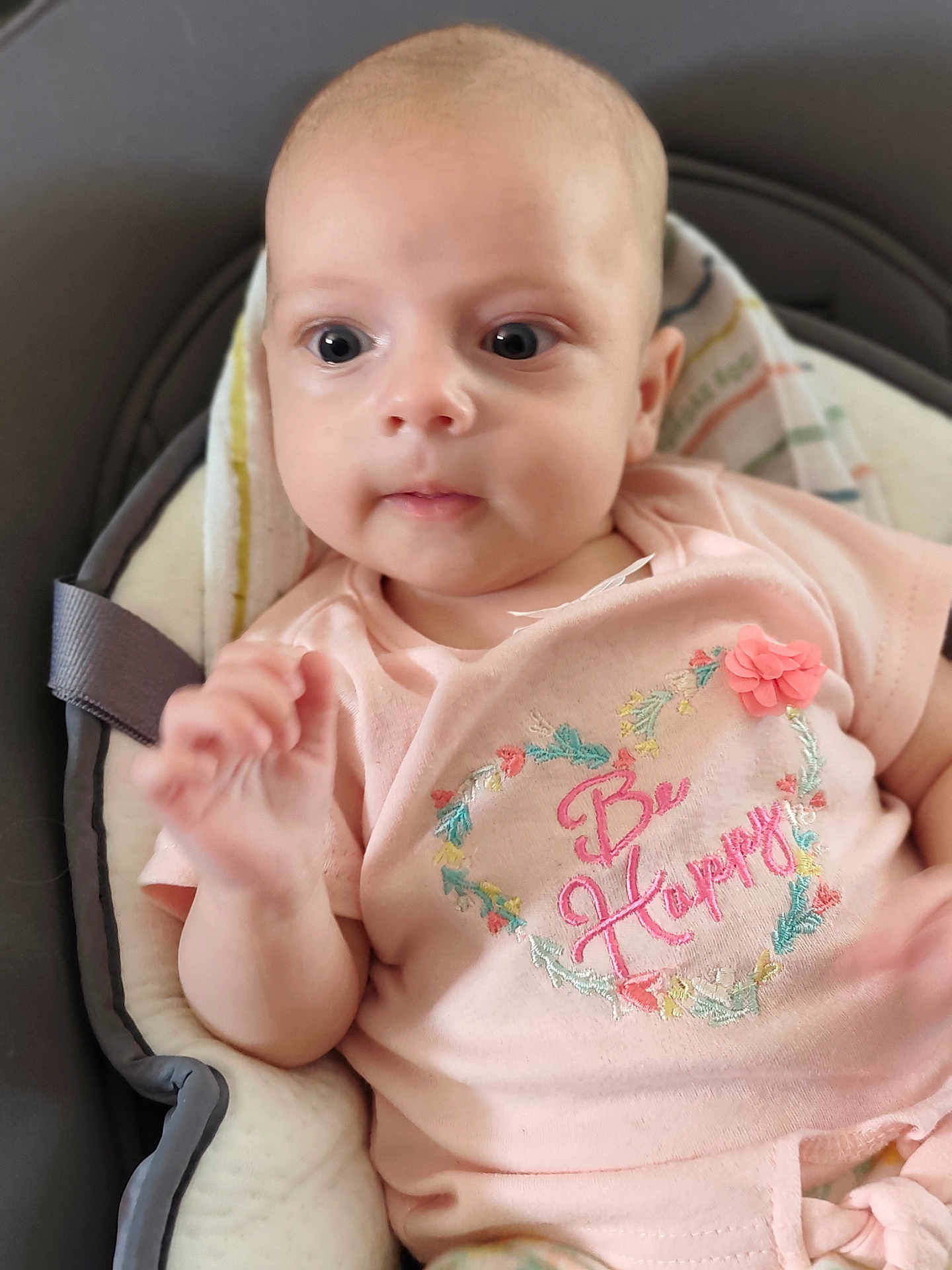 Linoa participe au concours pour gagner de l'argent avec cette photo : baby, infant, onesie, pink_clothing, embroidery, floral, face, hand, seat, cushion, curious, wide_eyes, indoors, soft_lighting, cute, child, newborn, portrait, happy_message, textile