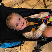 Lincoln joined the competition — help win amazing prizes! baby, child, stroller, toy, smile, happy, indoor, floor, clothing, seatbelt, person, cute, infant, play, colorful, legs, face, head, expression, young