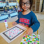 Ryan participe au concours pour gagner de l'argent avec cette photo : activity, child, classroom, colorful, education, floor, furniture, glasses, indoor, learning, person, play, shirt, sitting, stickers, table, tiles, toy, worksheet, young