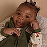 baby, smile, face, hair_buns, green_vest, pajamas, bear_pattern, blanket, infant, cute, child, portrait, cozy, happy, indoors, person, closeup, soft_texture, warm_colors, expression