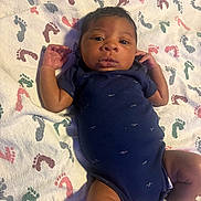 Kamere is registered to the contest to win money with this photo: baby, infant, blanket, footprint_pattern, onesie, blue_clothing, socks, lying_down, curious_expression, child, newborn, cute, small_hands, patterned_blanket, indoors, portrait, soft_lighting, head, face, skin