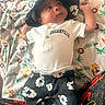 baby, infant, hat, clothing, blanket, animal_print, face, person, pattern, cute, lying_down, toddler, soft_texture, colorful, child, apparel, headwear, fabric, expression, indoors
