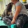 dog, person, child, kiss, affection, indoors, sitting, chair, window, sunlight, pet, companion, portrait, 家庭, clothing, leggings, spiderweb_pattern, teal, furniture, cuddling