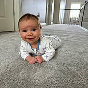 Archie is registered to the contest to win money with this photo: baby, infant, carpet, smiling, indoor, hallway, floor, clothing, person, cute, child, home, natural_light, window, door, white_wall, happy, lying_down, portrait, young_child