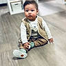 toddler, child, indoor, floor, vest, shoes, white_shirt, curious, sitting, baby, wooden_floor, casual_clothing, person, cute, portrait, young_child, hand, face, hair, home