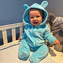 Kaven is registered to the contest to win money with this photo: baby, blue_onesie, crib, smiling, happy, face, baby_clothing, plush_toys, soft_lighting, indoors, child, cute, seated, baby_hugger, cozy, infant, hooded_outfit, baby_smile, toy, nursery