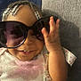 Autumn J is registered to the contest to win money with this photo: toddler, child, sunglasses, smile, beads, braids, face, hand, clothing, couch, fabric, happy, portrait, indoor, cute, person, baby, casual, relaxing, accessory