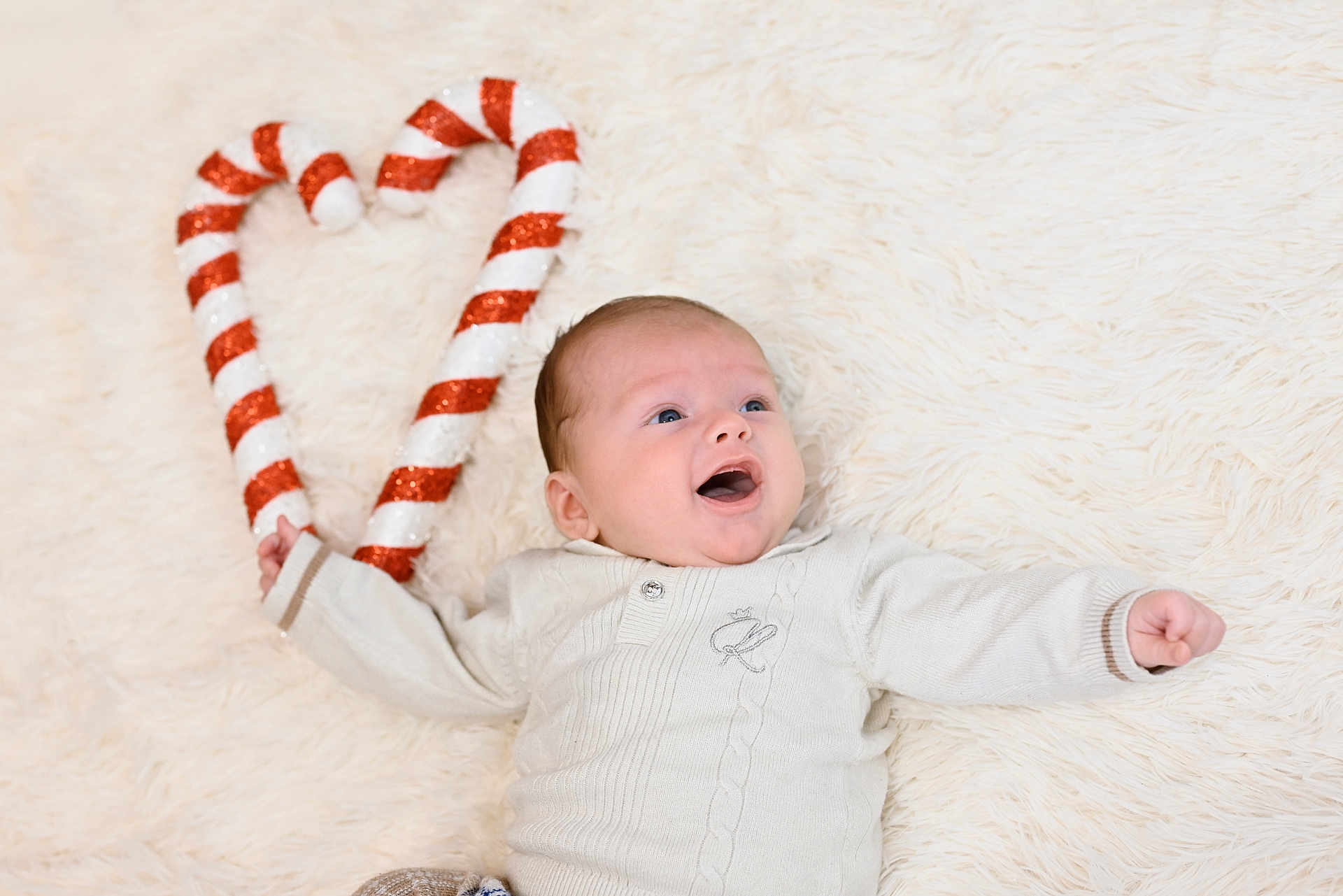 Bjorn joined the competition — help win amazing prizes! baby, infant, smiling, happy, candy_cane, heart_shape, white_sweater, blue_eyes, fluffy_rug, cozy, holiday, festive, cute, portrait, child, lying_down, celebration, sparkle, red_and_white, warm