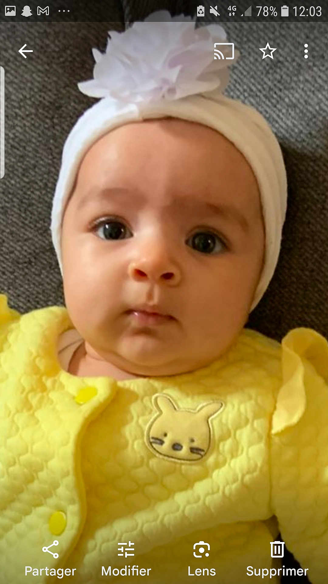 Naïsmée participe au concours pour gagner de l'argent avec cette photo : baby, infant, headband, flower, yellow_clothing, bunny_patch, cute, portrait, face, eyes, skin, child, young, indoors, texture, fabric, lying_down, soft_lighting, expression, closeup