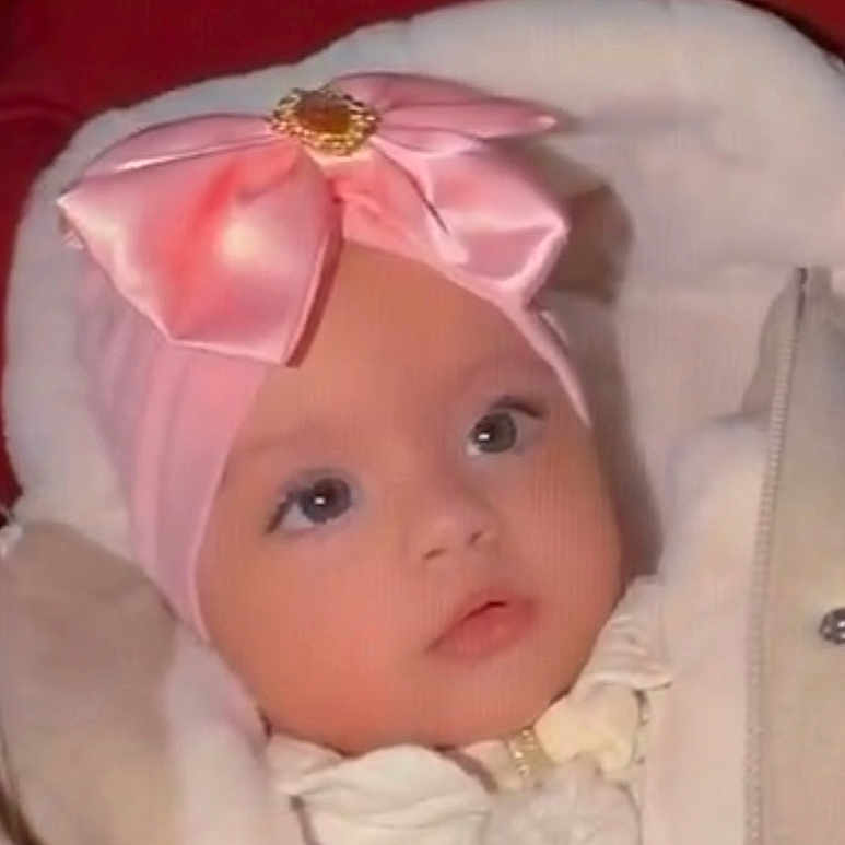 Beatrice participe au concours pour gagner de l'argent avec cette photo : baby, child, pink_bow, headwear, coat, warm_clothing, infant, face, portrait, seated, indoors, curious, cute, young_child, clothing, soft_fabric, closeup, winter_wear, seat, bundle