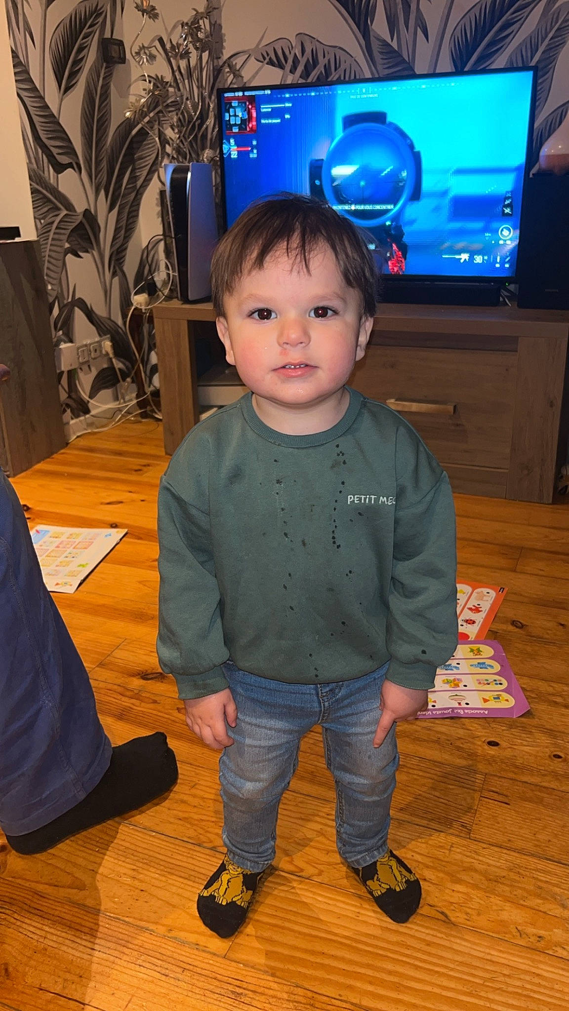 Andy a rejoint le concours — aidez-le/la à gagner de superbes lots ! baby_toddler_clothing, blue, cable_television, child, display_device, entertainment_center, floor, flooring, gadget, hardwood, home_appliance, houseplant, output_device, person, sleeve, standing, television, television_set, toddler, varnish