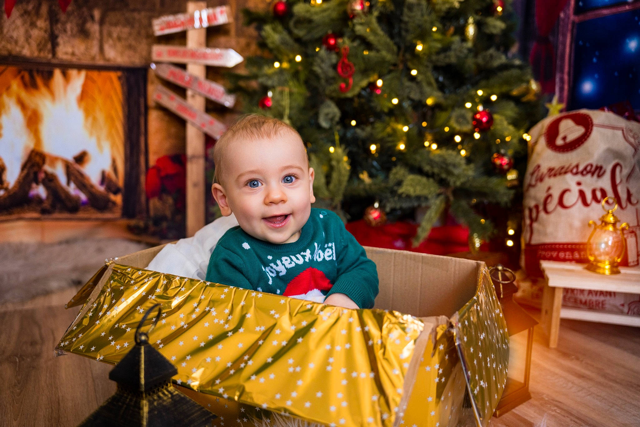 Rafaël participe au concours pour gagner de l'argent avec cette photo : child, christmas, christmas_decoration, christmas_eve, christmas_lights, christmas_ornament, christmas_tree, event, fireplace, fun, happy, holiday, joy, leisure, ornament, person, sitting, smile, toddler, tradition