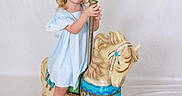 Presleigh joined the competition — help win amazing prizes! background, blonde_hair, blue_dress, carousel_horse, child, childhood, cute, floor, fun, girl, happy, indoor, play, pole, portrait, smile, toy, vintage, white_sandals, wooden_base