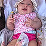 baby, infant, hat, pink_clothing, blanket, stroller, smiling, happy, face, hands, legs, diaper, floral_pattern, child, cute, soft_toys, cozy, relaxed, indoors, portrait