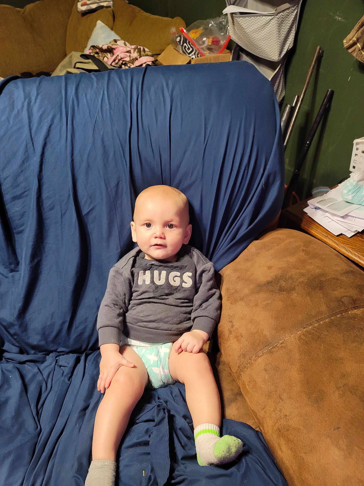 Nicco joined the competition — help win amazing prizes! baby, child, sitting, couch, socks, diaper, sweater, indoor, furniture, expression, face, person, living_room, blanket, blue_cover, brown_couch, curious, young_child, casual, home
