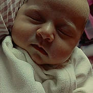 Kalia is registered to the contest to win money with this photo: baby, newborn, sleeping, infant, swaddled, blanket, close_up, portrait, face, closed_eyes, cheeks, nose, lips, head, cozy, soft_texture, fabric, striped_pillow, peaceful, indoors